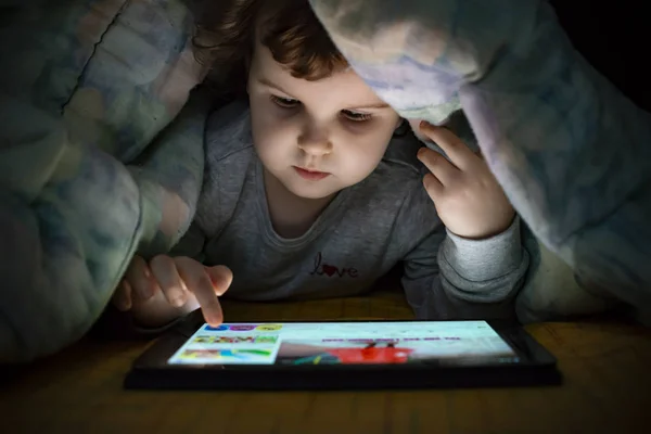 Menina observando seu tablet na cama. Criança iluminada fa — Fotografia de Stock