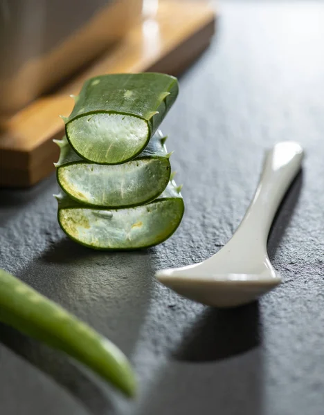 Żel Aloe vera plasterki na ciemnym tle i łyżka z aloesem. HEA — Zdjęcie stockowe