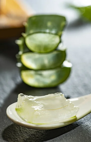 Aloe Vera Scheiben auf dunklem Hintergrund und Löffel mit Aloe Gel. hea — Stockfoto