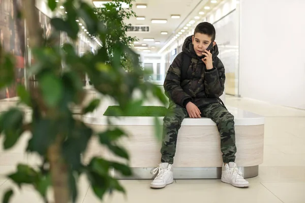 Adolescente hablando en el teléfono inteligente en el centro comercial moderno. Tecnología — Foto de Stock