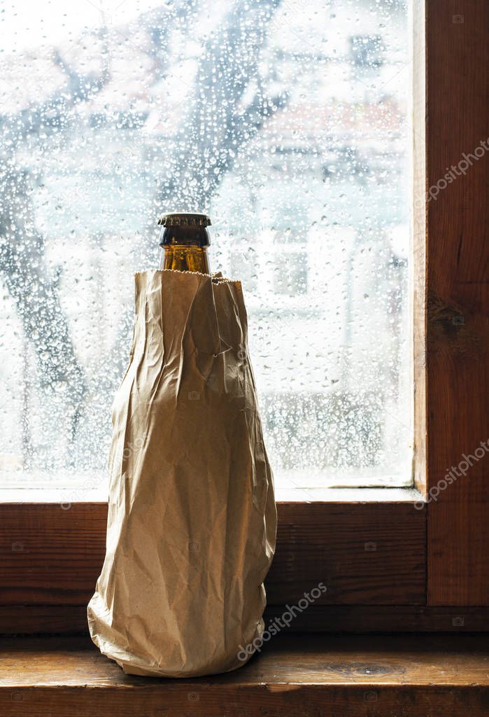 Bottle with alcohol in a brown pack paper placed to the window a