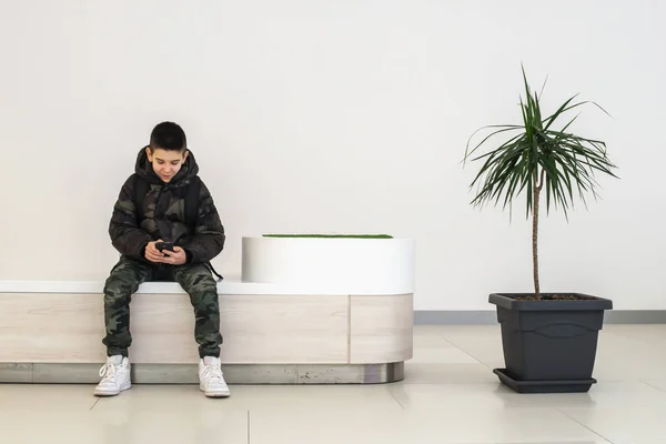 Adolescente jugando con smartphone en el centro comercial moderno. Te... — Foto de Stock