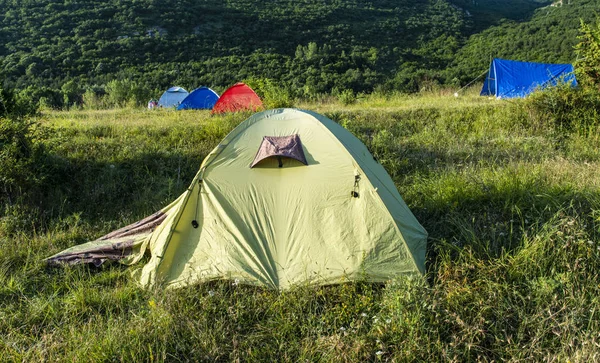 山にはたくさんのテントがある。森の中の太陽の光の朝. — ストック写真