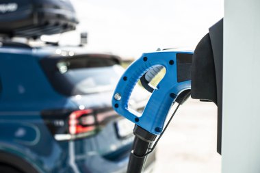 Benzin istasyonunda elektrikli araba. Mavi araba ve char için elektrik fişi