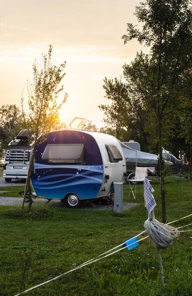 Caravans and campers on green meadow in campsite. Sunrise, rays — Stock Photo, Image