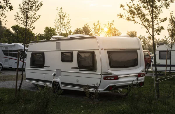 Caravan e camper su prato verde in campeggio. Alba, raggi — Foto Stock