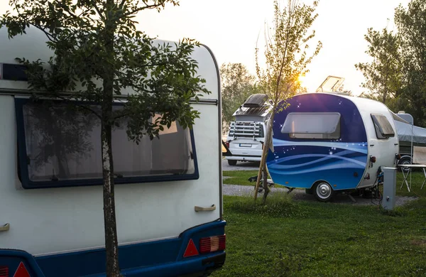 Caravans and campers on green meadow in campsite. Sunrise, rays — Stock Photo, Image