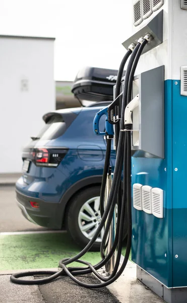 Coche eléctrico en gasolinera. Coche azul y enchufe eléctrico para carbón —  Fotos de Stock