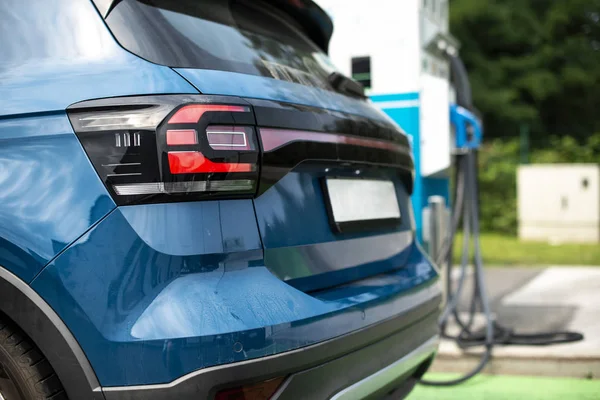 Elektrický vůz na benzínce. Modrá automobilovka a elektrická zástrčka pro char — Stock fotografie