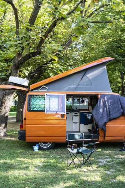 Camper in campsite. Outdoor equipment and travel van on green me — Stock Photo, Image