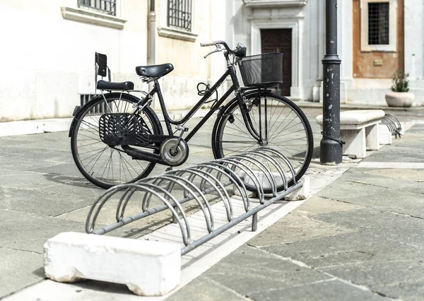 Black bike mounted on a bicycle stand on italian street. — Stock Photo, Image