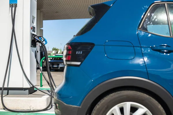 Elektrische auto op benzinestation. Blauwe auto en elektrische stekker voor char — Stockfoto