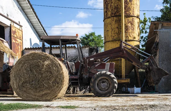 Traktor a gazdaságban. Bála széna az előtérben. — Stock Fotó