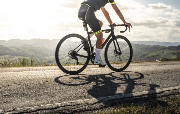 Fietser sporten op de weg. Zonnestralen en schaduwen van de fiets op th — Stockfoto