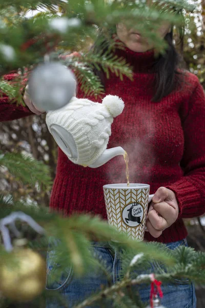 Женщина наливает чай с чайником в чашку. Рождественская елка — стоковое фото