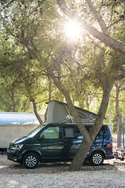 Donkerblauwe camper op de camping. Ochtendzon. — Stockfoto