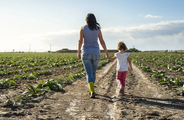 Mujer agricultora y niña caminando en la tierra de la agricultura . Fotos de stock libres de derechos