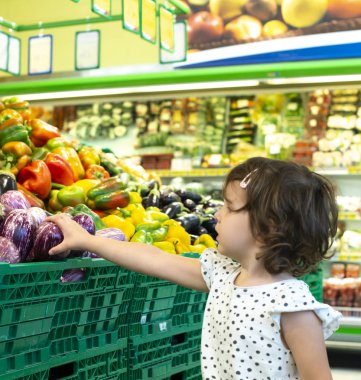 Süpermarkette patlıcan alışverişi yapan çocuk. Meyve almak için kavram