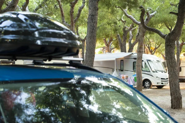 Auto met bagageruimte bovenop. Camper op achtergrond op de camping. — Stockfoto