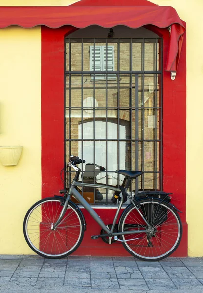 Szary rower przed żółtą fasadą i czerwonym oknem. rower z — Zdjęcie stockowe