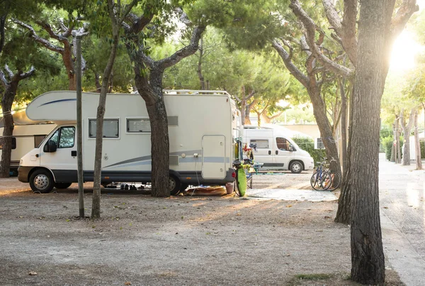 Camper blanco en el camping. Muchas bicicletas y caravanas en camping . Imagen de stock