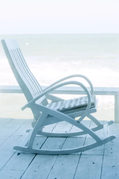 wooden terrace at sea and rocking chair with pillow, vertical image
