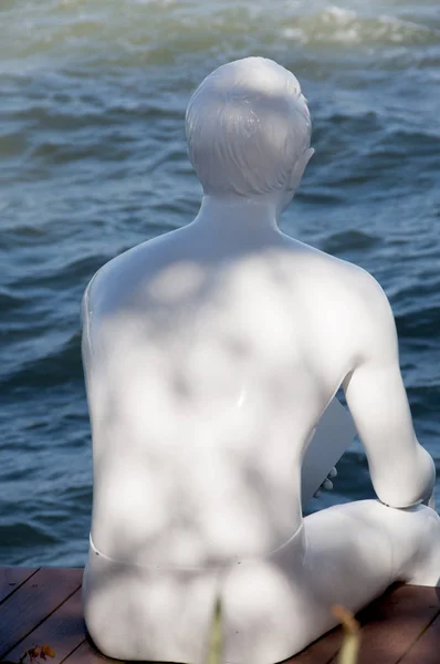 back view of white sculpture sitting at sea water