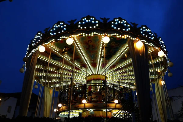  terasa aşağı, geceleri carousal aydınlatma içinde tahterevalli eğlence parkı görünümü 