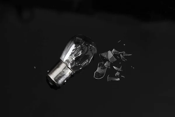 Broken Lamp with Shattered Pieces on Dark Reflective Background, Failure Concept
