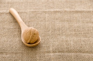 Çuval arka plan üzerinde tahta bir kaşık ceviz