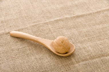 Çuval arka plan üzerinde tahta bir kaşık ceviz