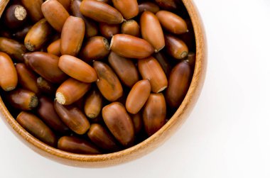 beyaz arka plan üzerinde ahşap yuvarlak kase meşe palamudu