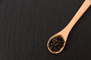 Kara biberli tahta kaşık. Siyah taş tabakta.