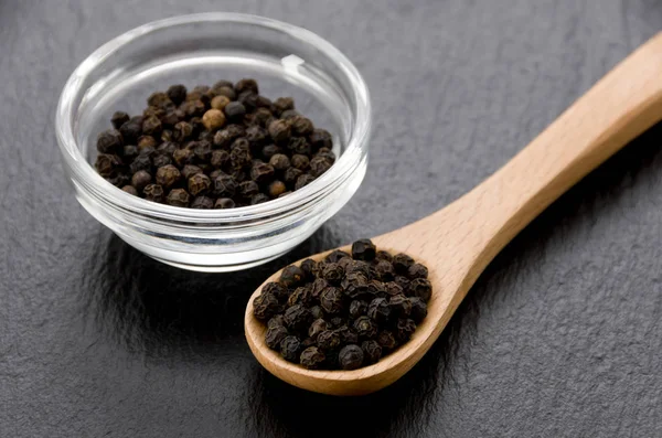 Zwarte Peper Stapelbak Met Houten Lepel Zwarte Stenen Plaat — Stockfoto