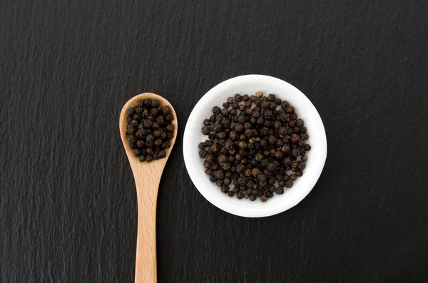 Zwarte Peper Witte Schaal Met Houten Lepel Zwarte Stenen Plaat — Stockfoto