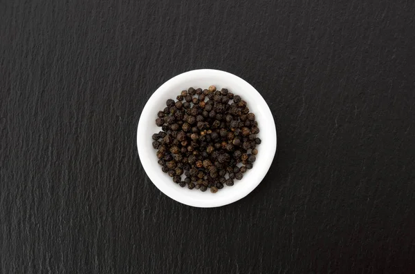 ブラックストーンプレート上の白い皿の黒コショウ — ストック写真