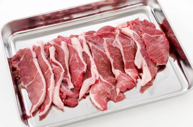 Beyaz arka planda paslanmaz çelik tepside çiğ kuzu eti..