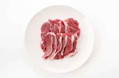 Raw lamb meat on a white plate on white background
