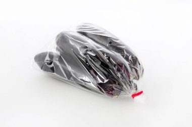 Beyaz arka planda plastik poşette çiğ siyah patlıcan.