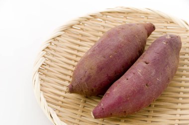 Çiğ Japon tatlı patatesleri beyaz arka planda bambu elek üzerinde