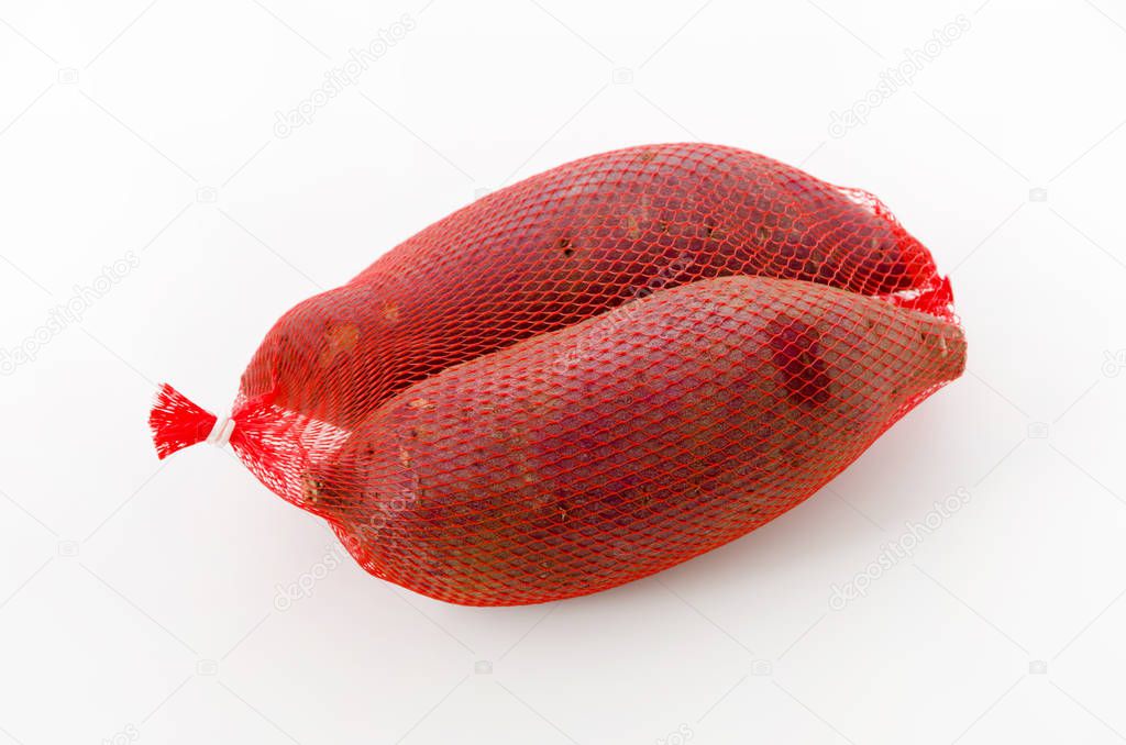 Raw Japanese sweet potatoes in a net bag on white background