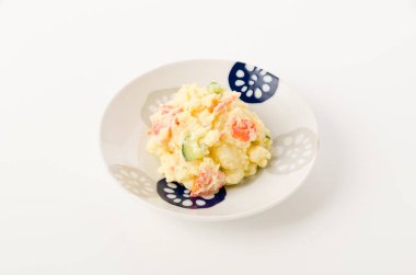 Beyaz arka planda beyaz tabakta patates salatası