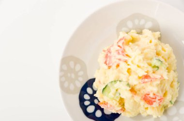 Beyaz arka planda beyaz tabakta patates salatası