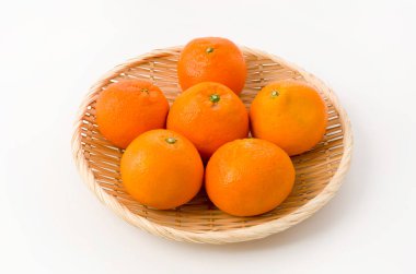 Beyaz arka planda bambu süzgeci üzerine taze Citrus iyo Japon narenciye meyveleri Iyokan