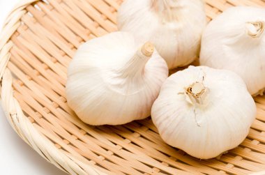 Beyaz arka planda bambu kevgire sarımsak.