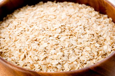 Beyaz arka planda ahşap bir kasede yulaf ezmesi.