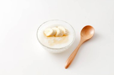 Beyaz arka planda muz dilimleri olan yoğurt.