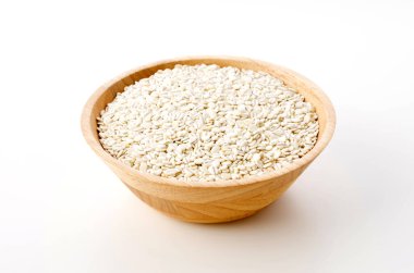 Beyaz arka planda ahşap bir kasede yuvarlanmış arpa.