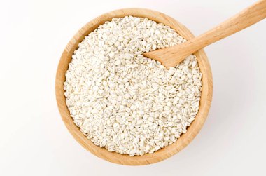 Beyaz arka planda ahşap bir kasede yuvarlanmış arpa.