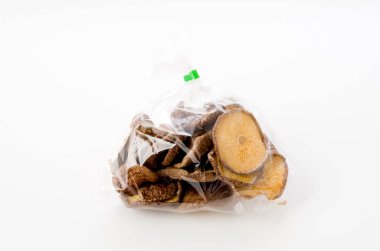 Beyaz arka planda plastik poşette kurutulmuş bok mantarı.